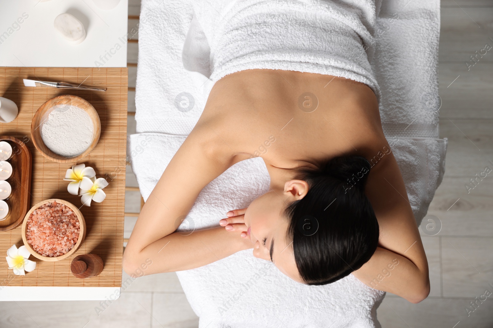 Photo of Beautiful woman relaxing on massage table in spa salon, top view