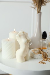 Beautiful female body shaped candle on white table. Stylish decor