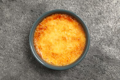 Delicious creme brulee in ceramic ramekin on grey table, top view