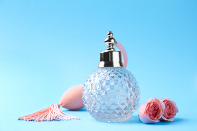 Photo of Bottle of perfume and flowers on light blue background