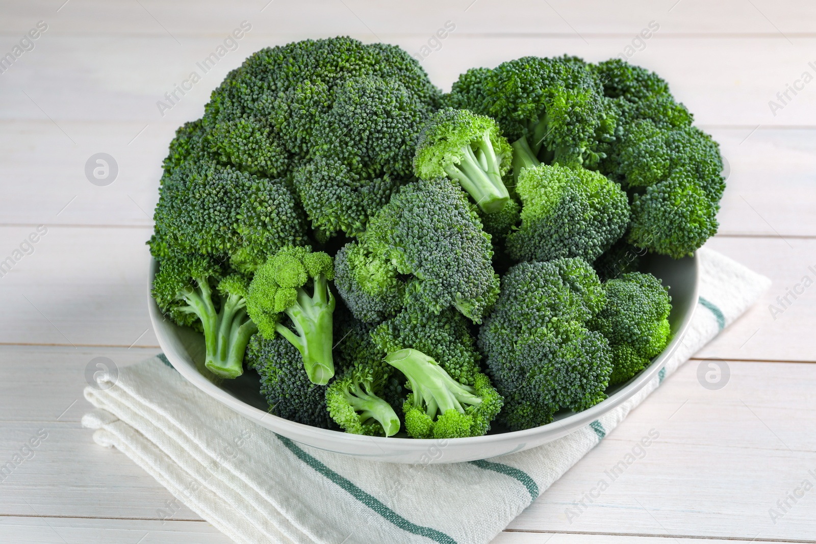 Photo of Bowl of fresh raw broccoli on white wooden table