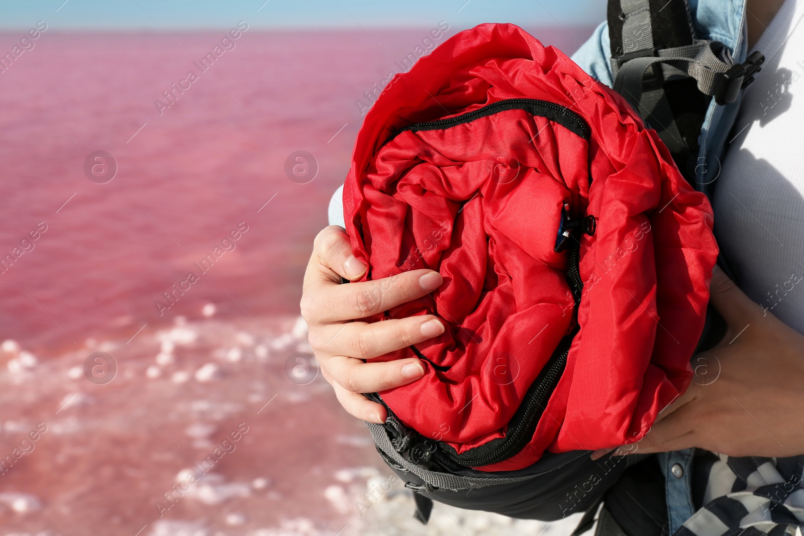 Photo of Woman with sleeping bag on coast of pink lake