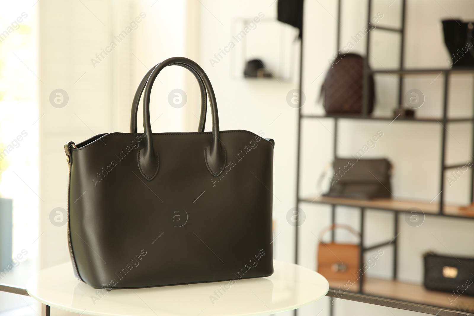 Photo of Stylish woman's bag on stand in boutique. Space for text