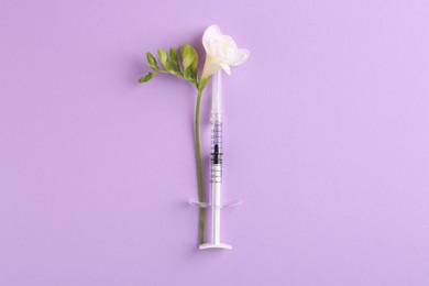 Photo of Cosmetology. Medical syringe and freesia flower on violet background, top view