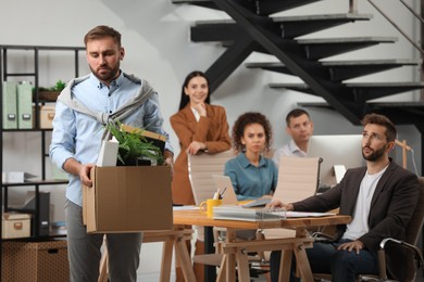 Upset dismissed man carrying box with stuff in office, space for text