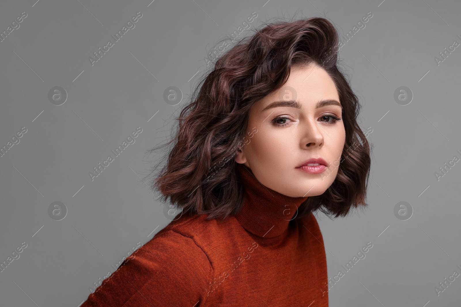 Photo of Portrait of beautiful young woman with wavy hairstyle on grey background