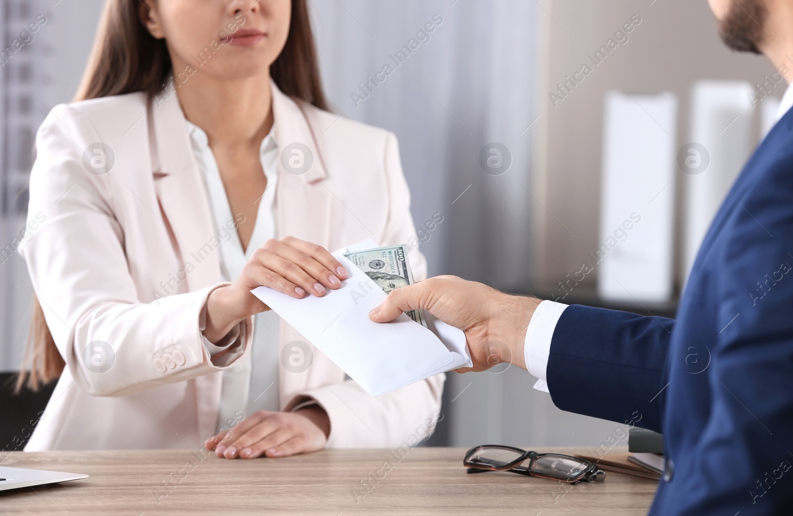 Photo of Man giving bribe to woman at table in office, closeup