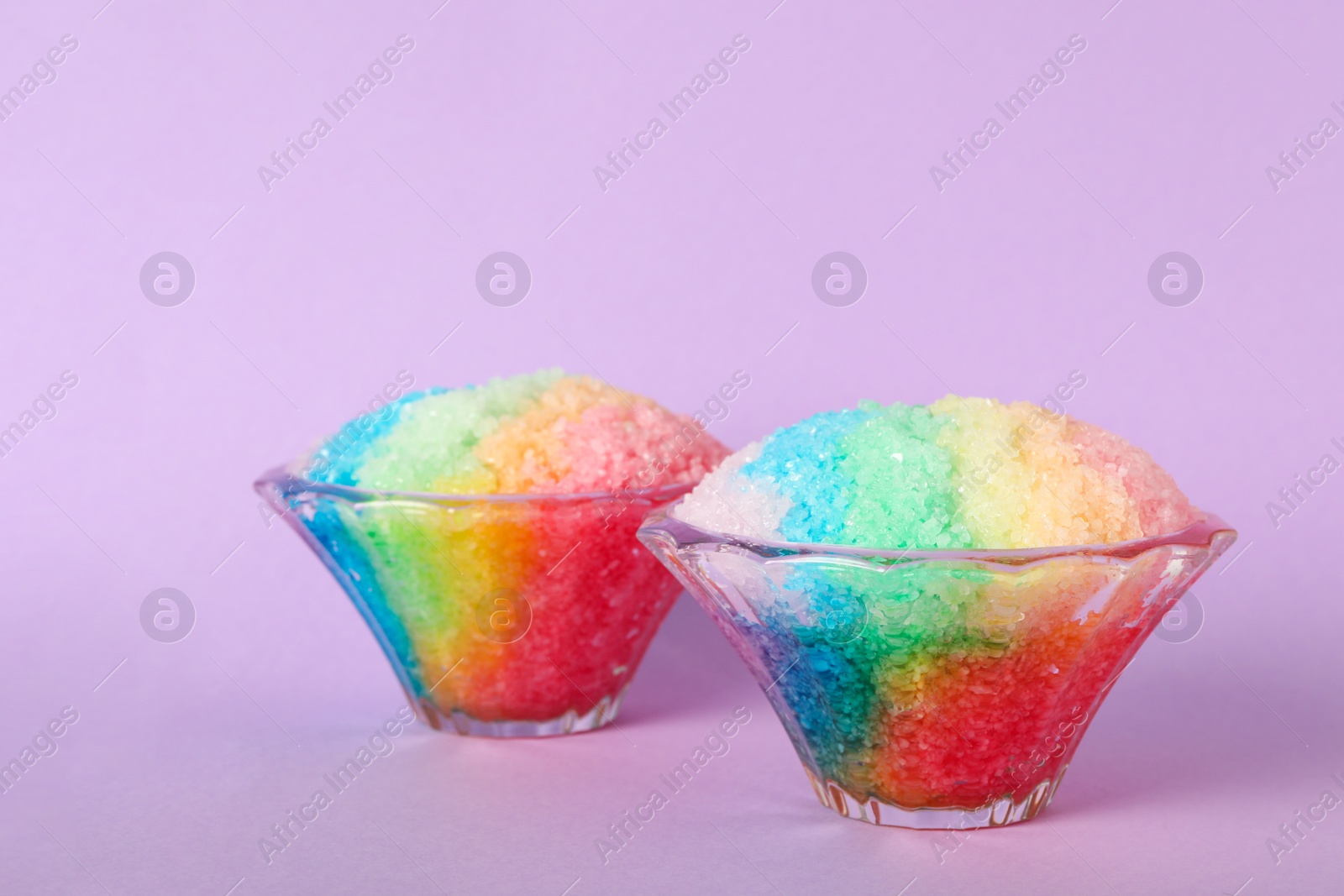 Photo of Rainbow shaving ice in glass dessert bowls on violet background