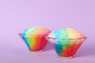 Photo of Rainbow shaving ice in glass dessert bowls on violet background