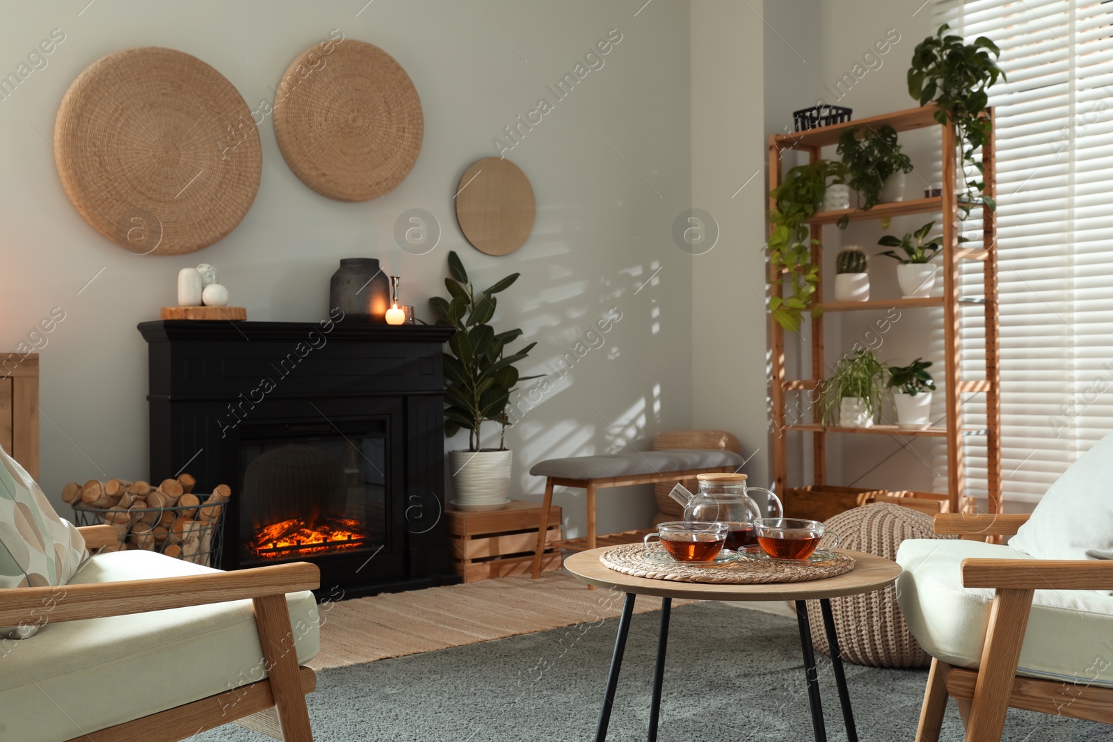 Photo of Stylish fireplace near coffee table with tea in cosy living room. Interior design