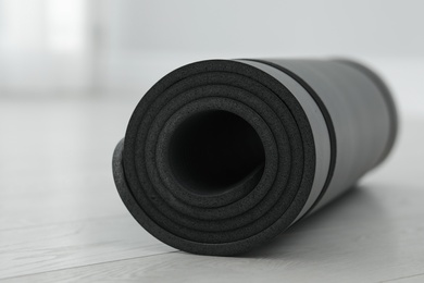 Photo of Rolled yoga mat on wooden floor, closeup