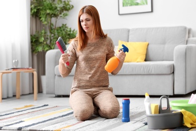 Photo of Tired housewife cleaning carpet in living room