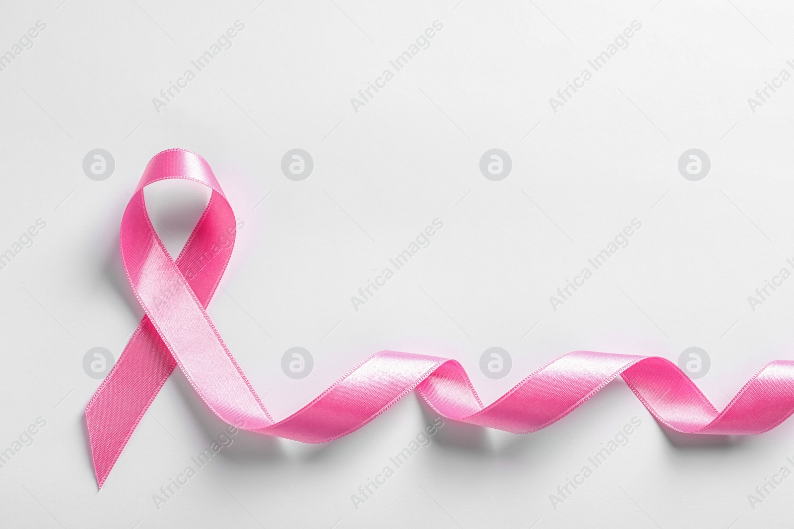 Photo of Pink ribbon on white background, top view. Cancer awareness