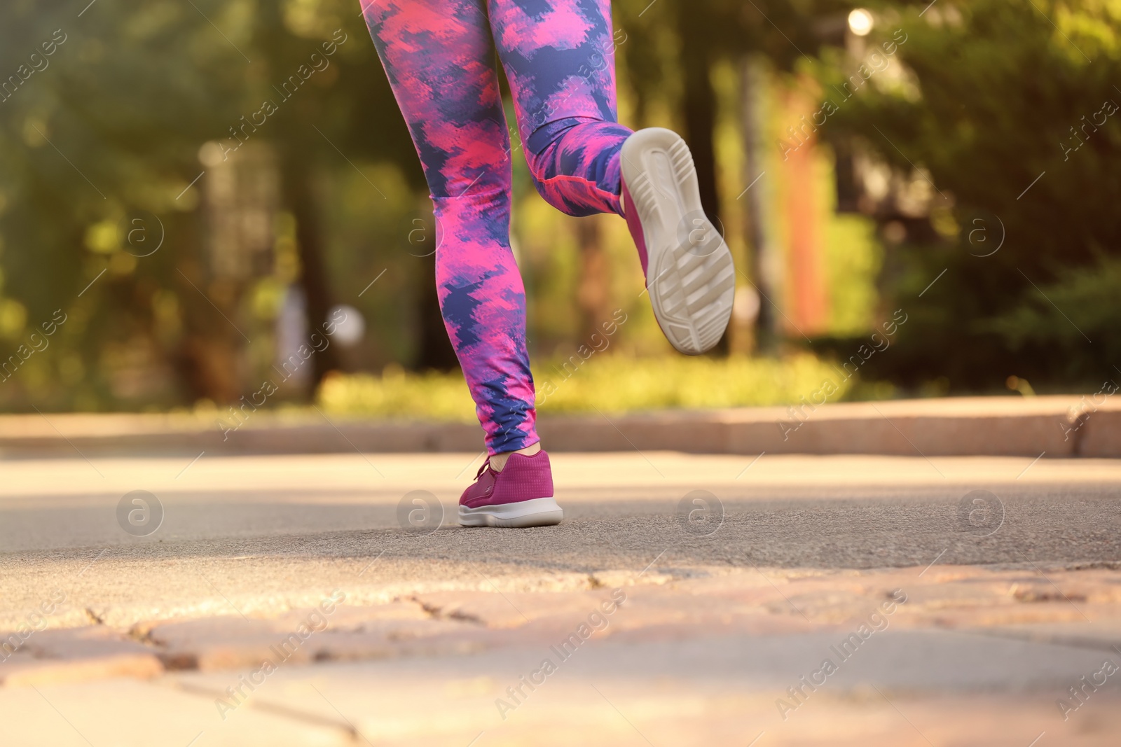 Photo of Young woman running in park on sunny day, focus on legs