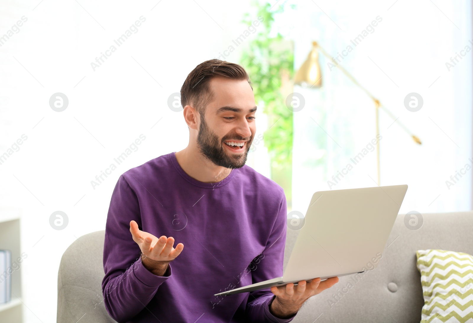 Photo of Man using laptop for video chat in living room