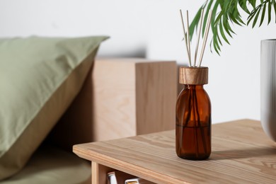 Aromatic reed air freshener on wooden table indoors. Space for text