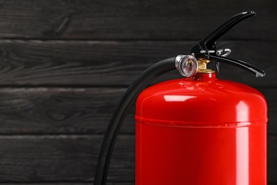 Fire extinguisher against wooden wall, closeup. Space for text