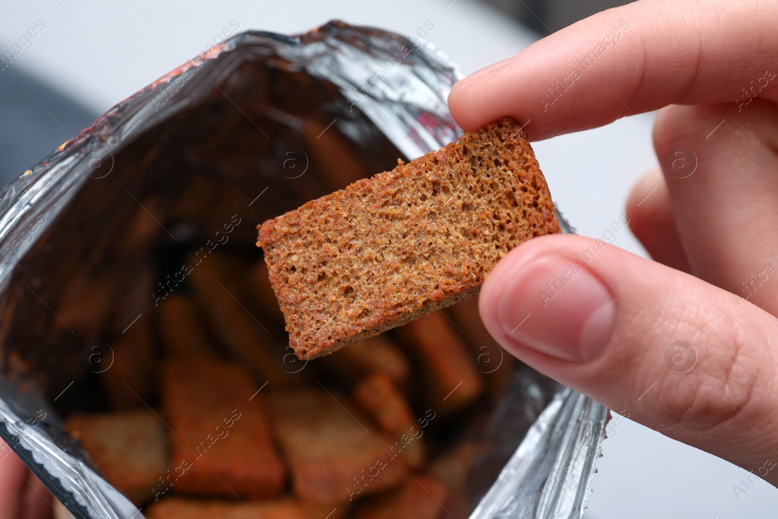 Photo of Woman taking crispy rusk out of package, closeup