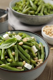 Photo of Delicious salad with green beans, pine nuts and cheese on table, closeup