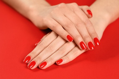 Photo of Woman showing manicured hands with red nail polish on color background, closeup