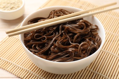 Photo of Tasty buckwheat noodles (soba) with chopsticks on table, closeup