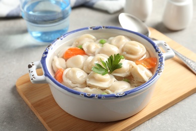 Photo of Board with bowl of dumplings in broth on table