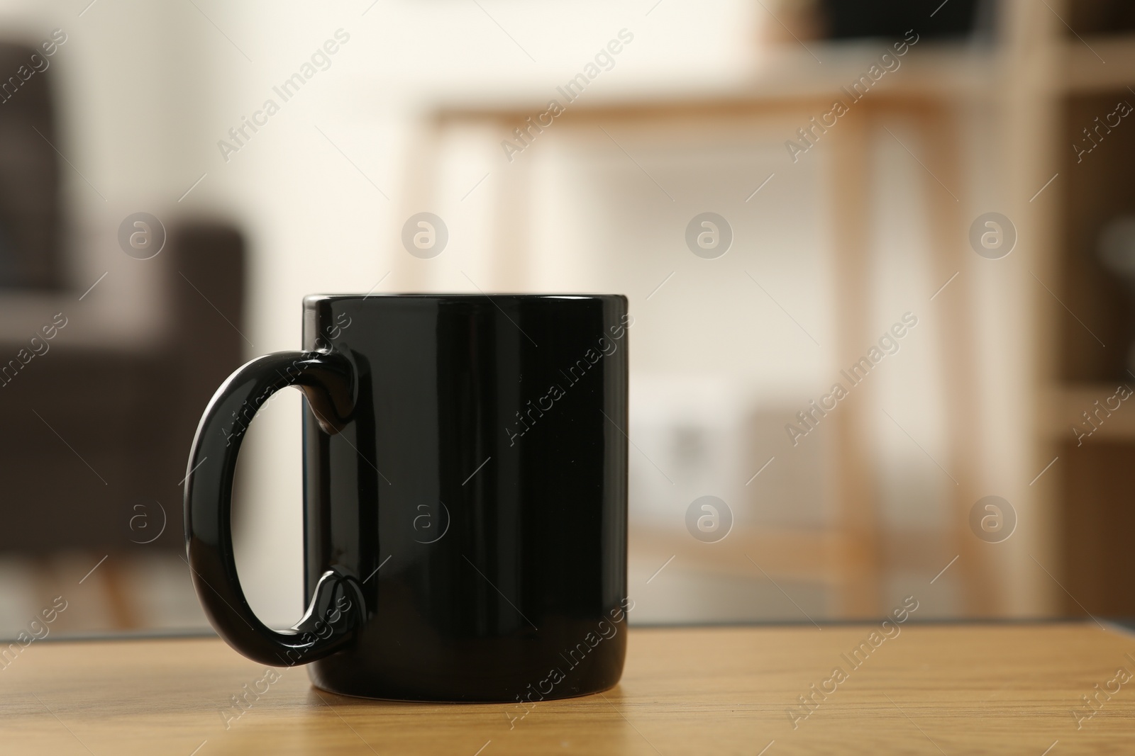 Photo of Black mug on wooden table indoors. Mockup for design