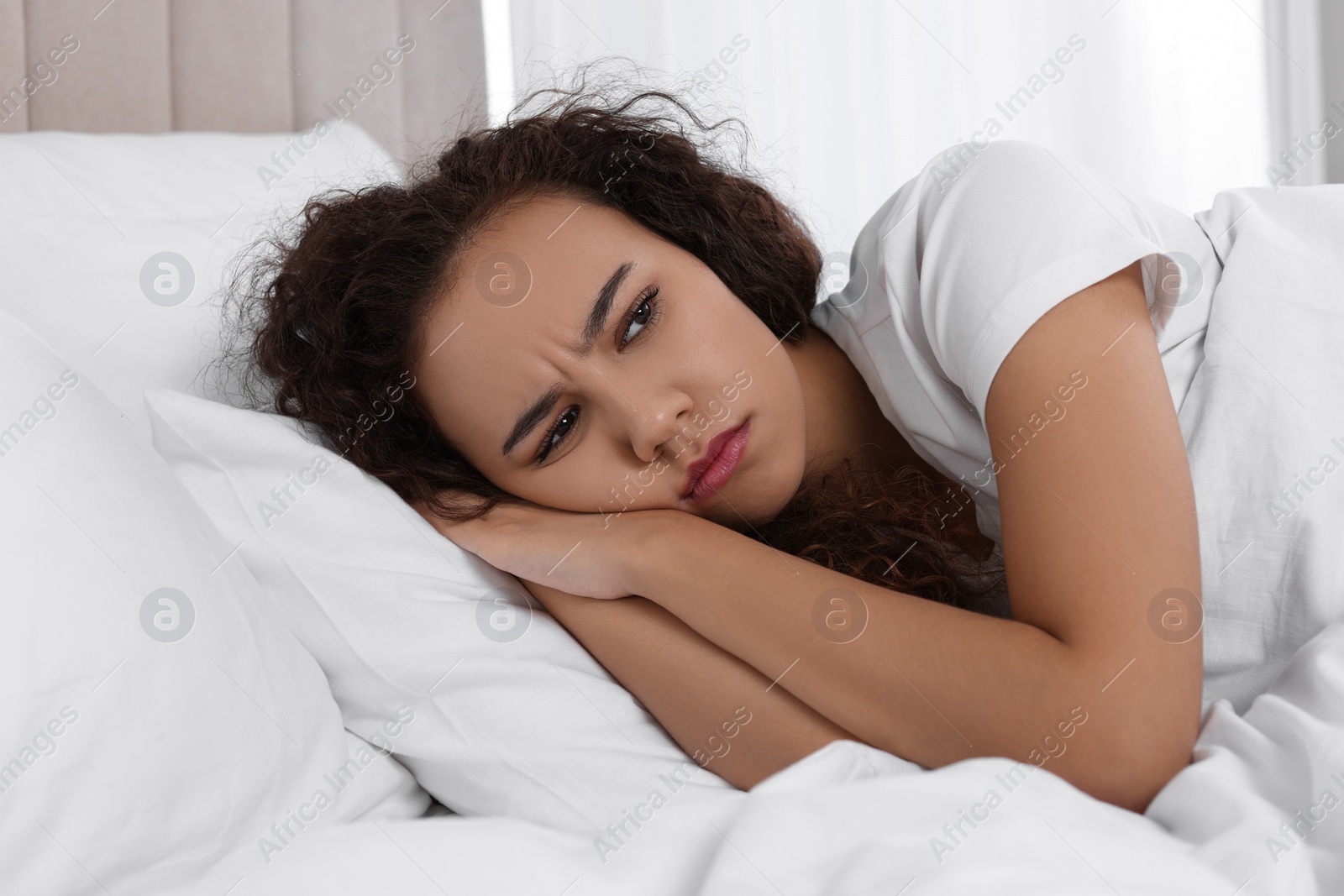 Photo of Unhappy African American woman in bed at home