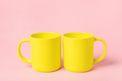 Two yellow ceramic mugs on pink background