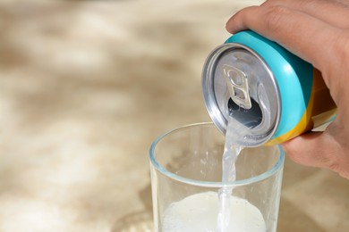 Photo of Woman pouring drink from aluminum can into glass at table, closeup. Space for text