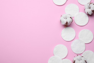 Photo of Soft clean cotton pads and flowers on pink background, flat lay. Space for text