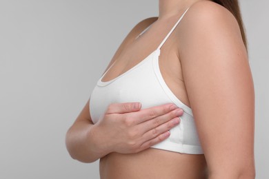 Mammology. Woman doing breast self-examination on light grey background, closeup