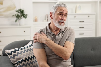 Arthritis symptoms. Man suffering from pain in shoulder at home