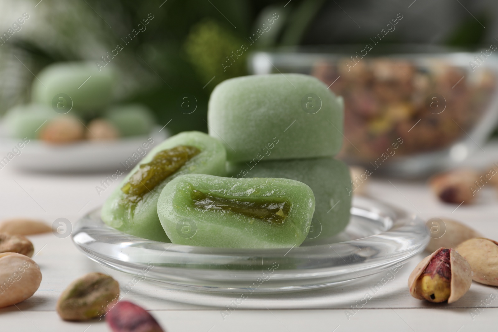Photo of Delicious mochi and pistachios on white table, closeup. Traditional Japanese dessert
