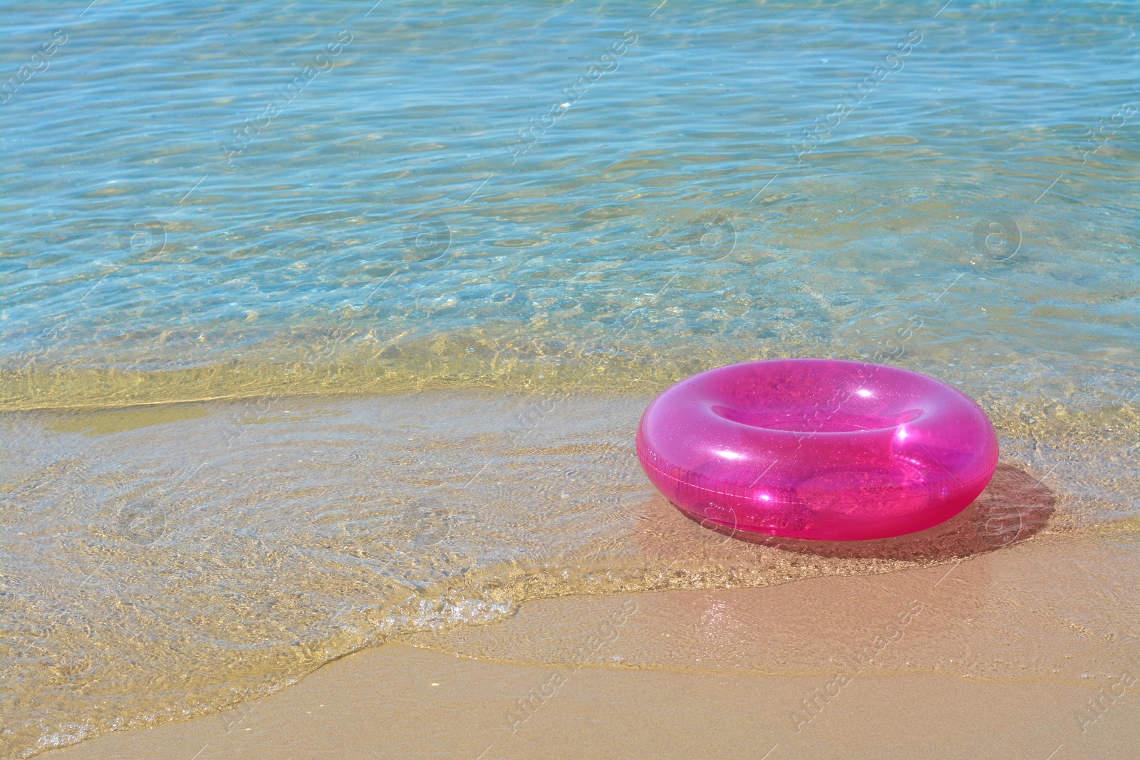 Photo of Bright inflatable ring on sandy beach near sea. Space for text