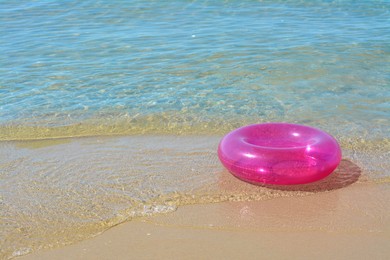Photo of Bright inflatable ring on sandy beach near sea. Space for text