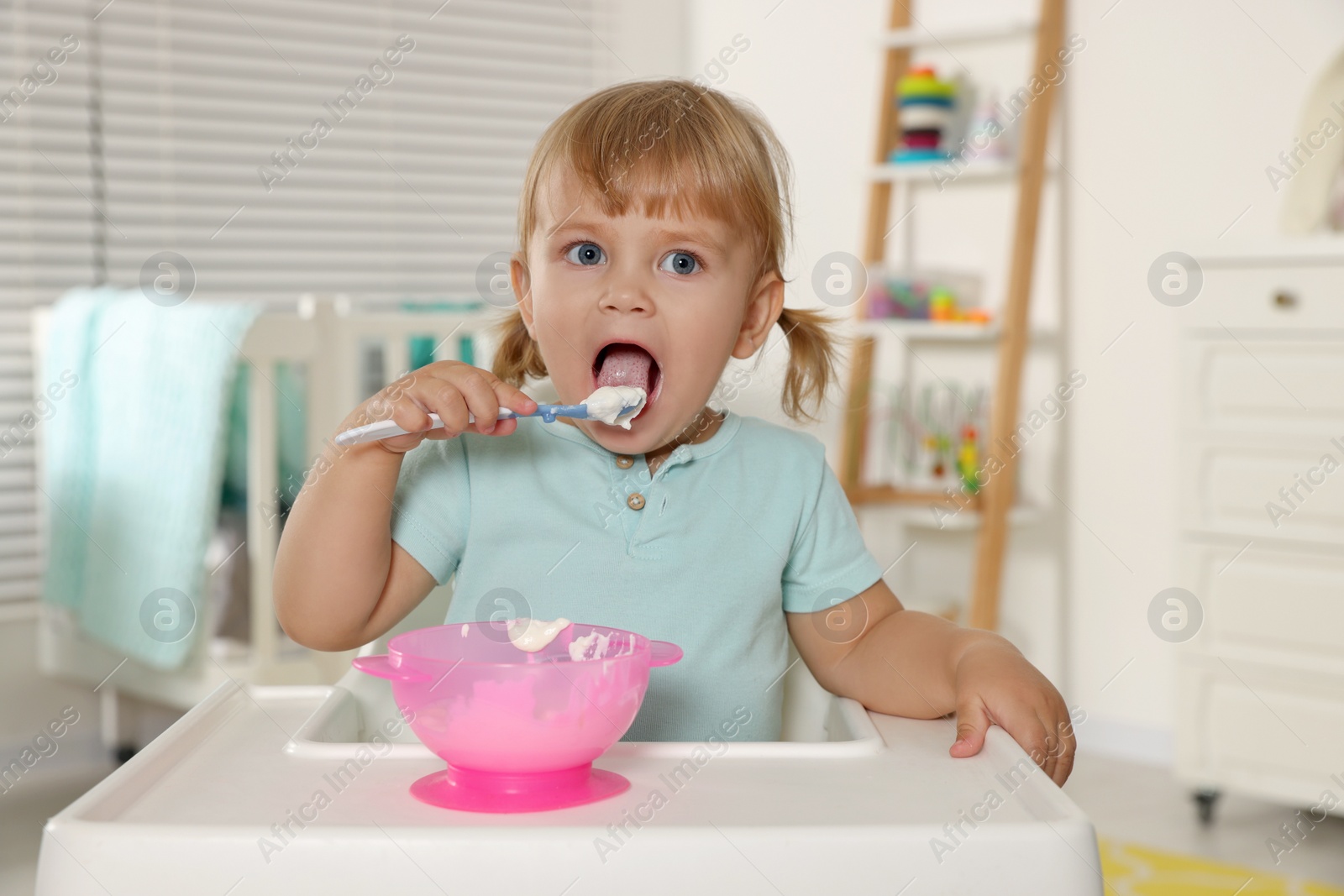 Photo of Cute little child eating tasty yogurt with spoon at home