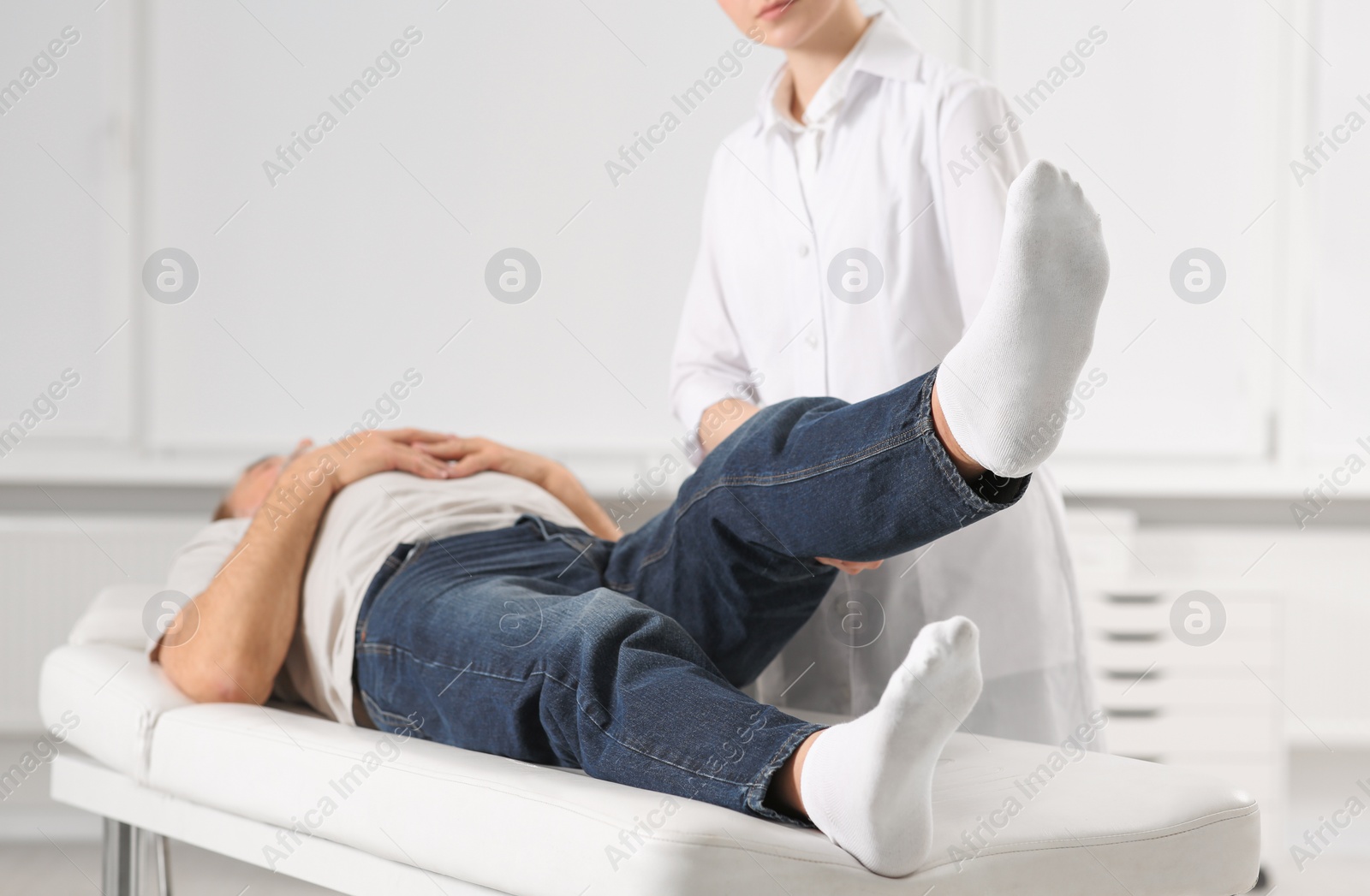 Photo of Professional orthopedist examining patient's leg in clinic, closeup