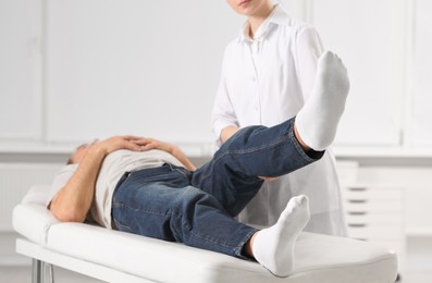 Professional orthopedist examining patient's leg in clinic, closeup