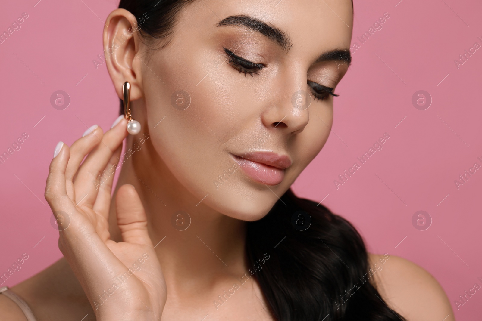 Photo of Young woman wearing elegant pearl earrings on pink background, closeup