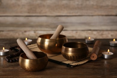 Photo of Golden singing bowls and mallets on wooden table