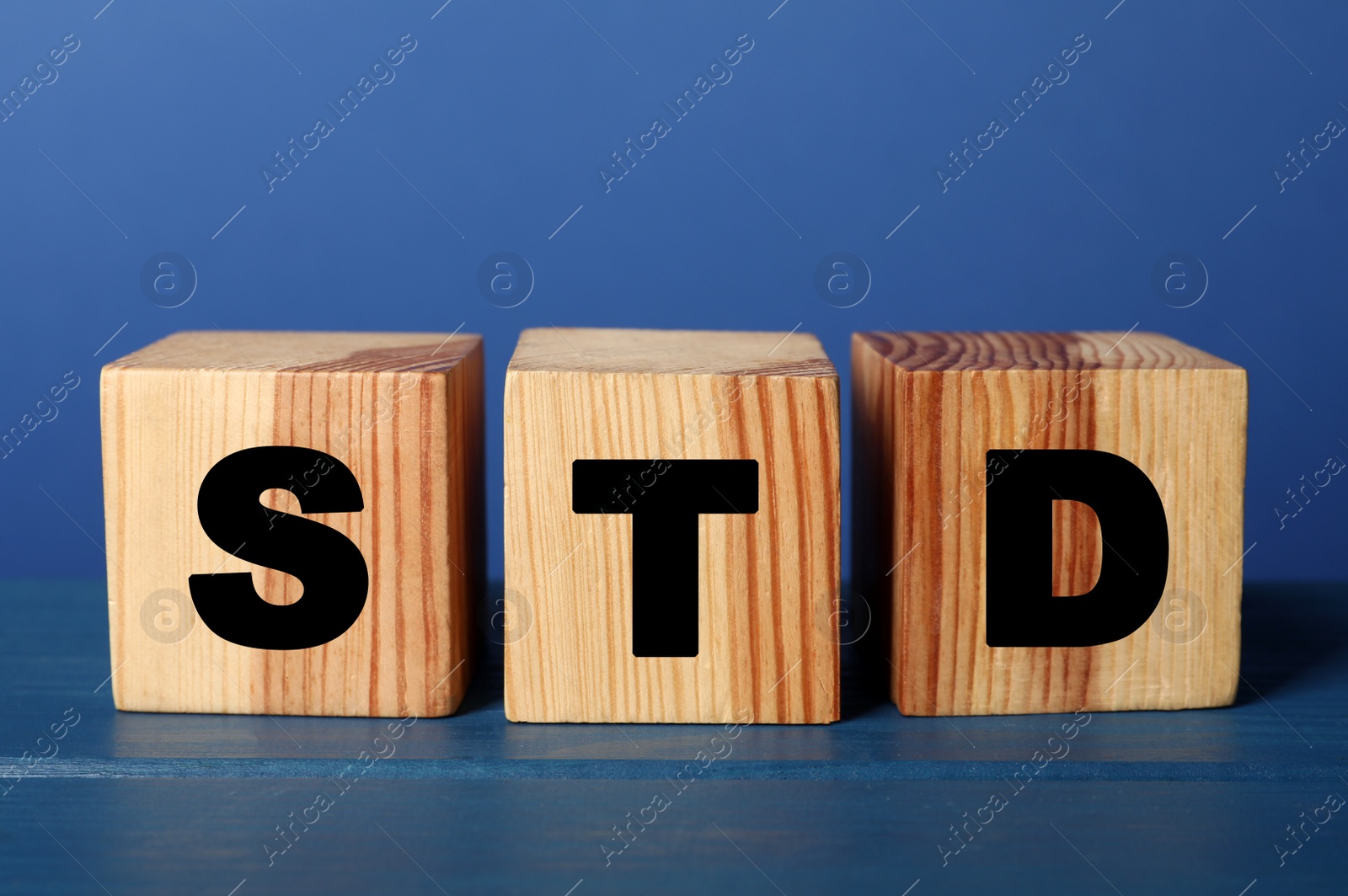 Photo of Wooden cubes with letters STD (sexually transmitted diseases) on blue table