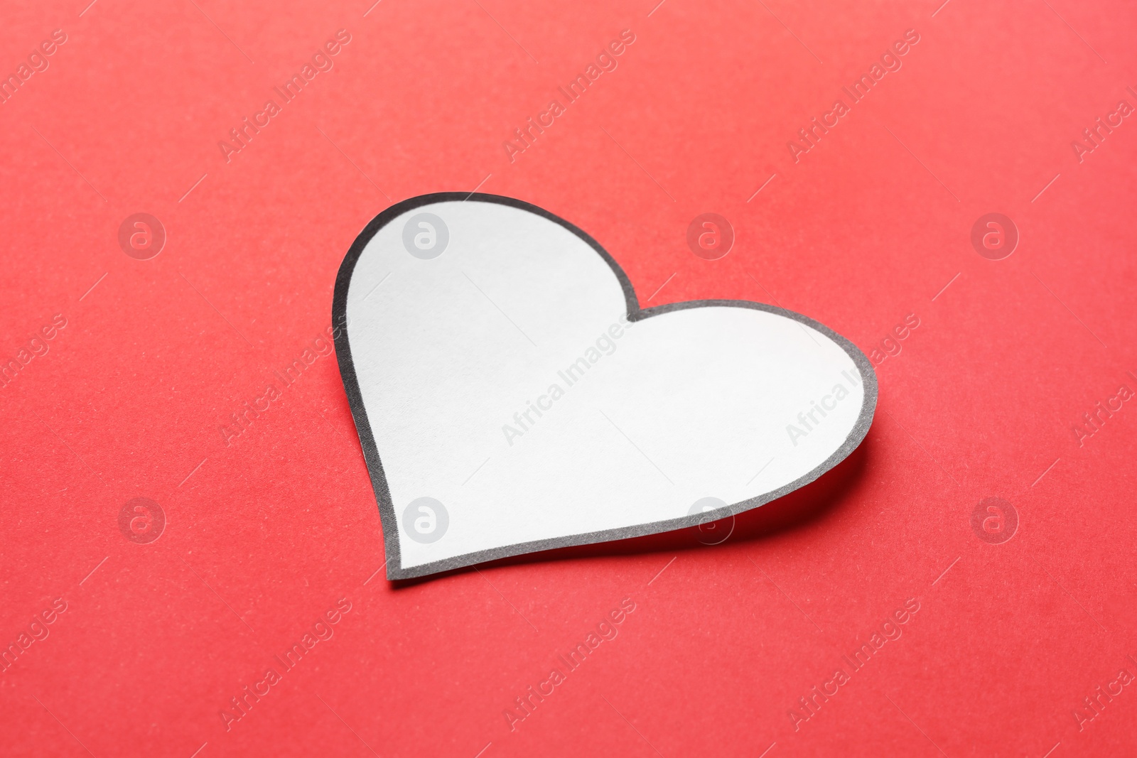 Photo of One white paper heart on red background