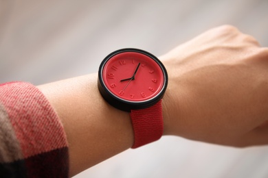 Woman with stylish wrist watch on blurred background, closeup. Time management