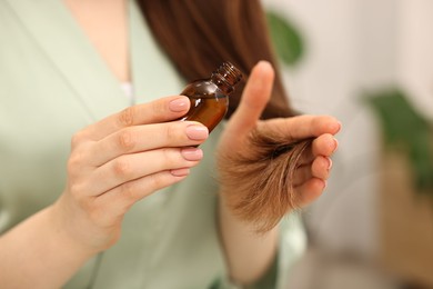 Woman applying oil hair mask indoors, closeup