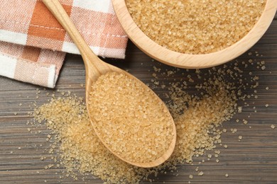 Photo of Brown sugar in bowl and spoon on wooden table, flat lay