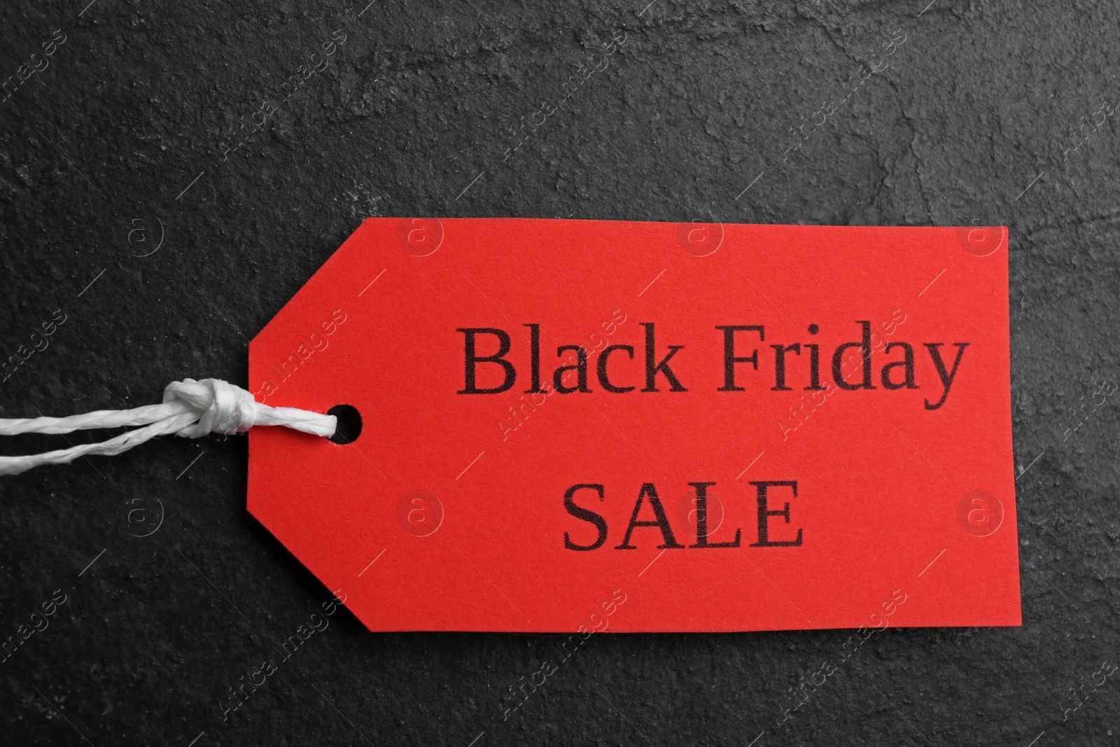 Photo of Red tag with words BLACK FRIDAY SALE on dark slate background, top view