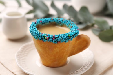Photo of Delicious edible biscuit cupespresso decorated with sprinkles on table, closeup