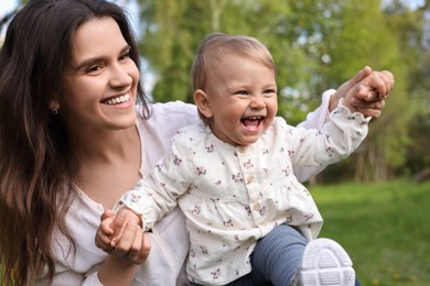 Happy mother with her cute baby in park on sunny day