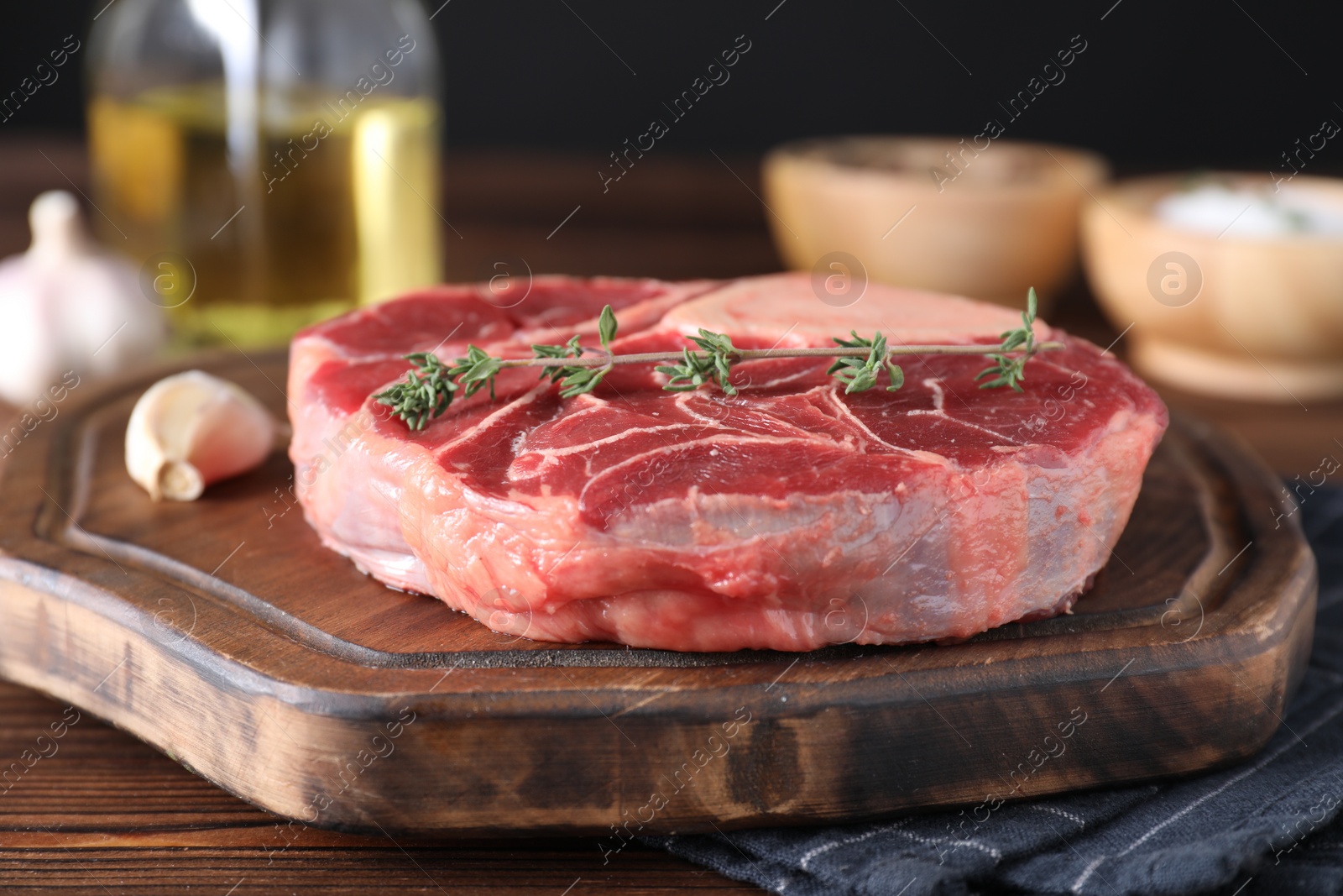 Photo of Piece of raw beef meat and thyme on wooden table, closeup